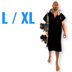 L/XL WOLV Surf Poncho gedragen door een model van 1.90 m met wakeboard, losse pasvorm tot op de knie