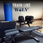 Opgerolde blauwe WOLV yogamat in een home gym opstelling met verstelbare dumbbells en verstelbare bank