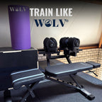 Paarse WOLV yogamat rechtop gerold in een home gym met dumbbells, rek en halterbank