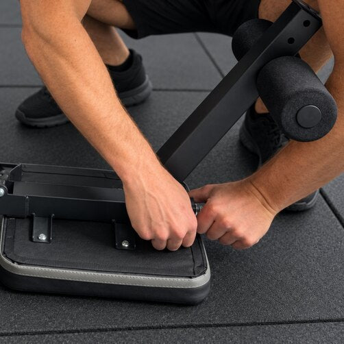 Hands assembling a WOLV adjustable bench on rubber gym flooring